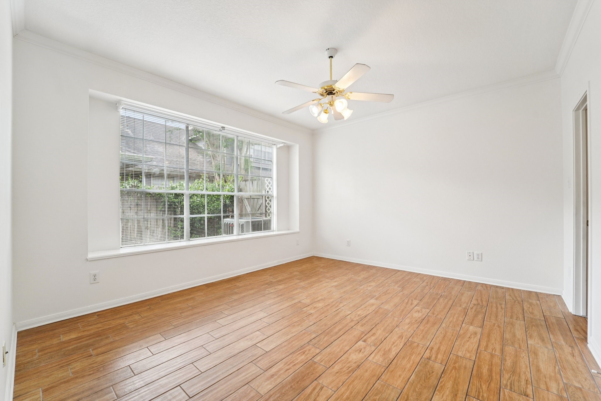 14420 Walters Road, Unit 55 Houston, TX 77014 - Photo 20 of 35 Bright room with wood-look flooring, large window, and ceiling fan, offering ample natural light. Perfect for a cozy living area or office space.