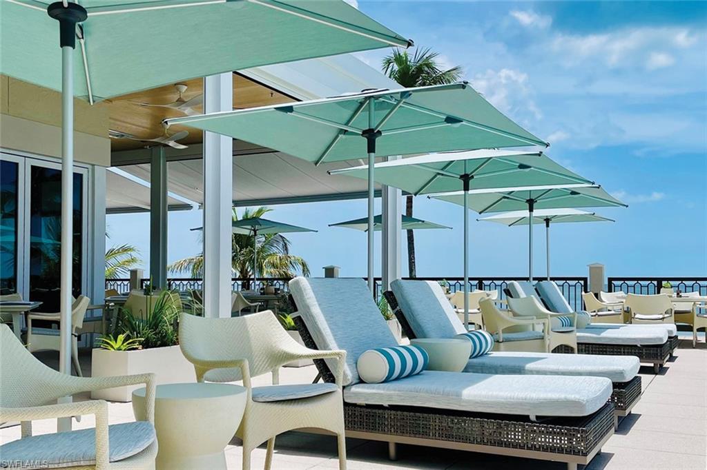 15547 Monterosso Lane, Unit 201 Naples, FL 34110 - Photo 49 of 50 a roof deck with table and chairs under an umbrella