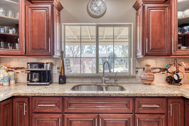 a kitchen with granite countertop a sink a stove and cabinets