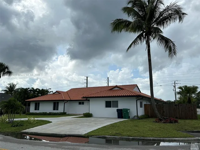 a view of house with garden and tall tress