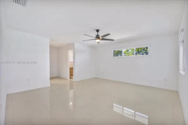 an empty room with windows and ceiling fan