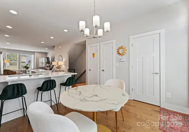 a dining room with wooden floor a chandelier a wooden table and chairs