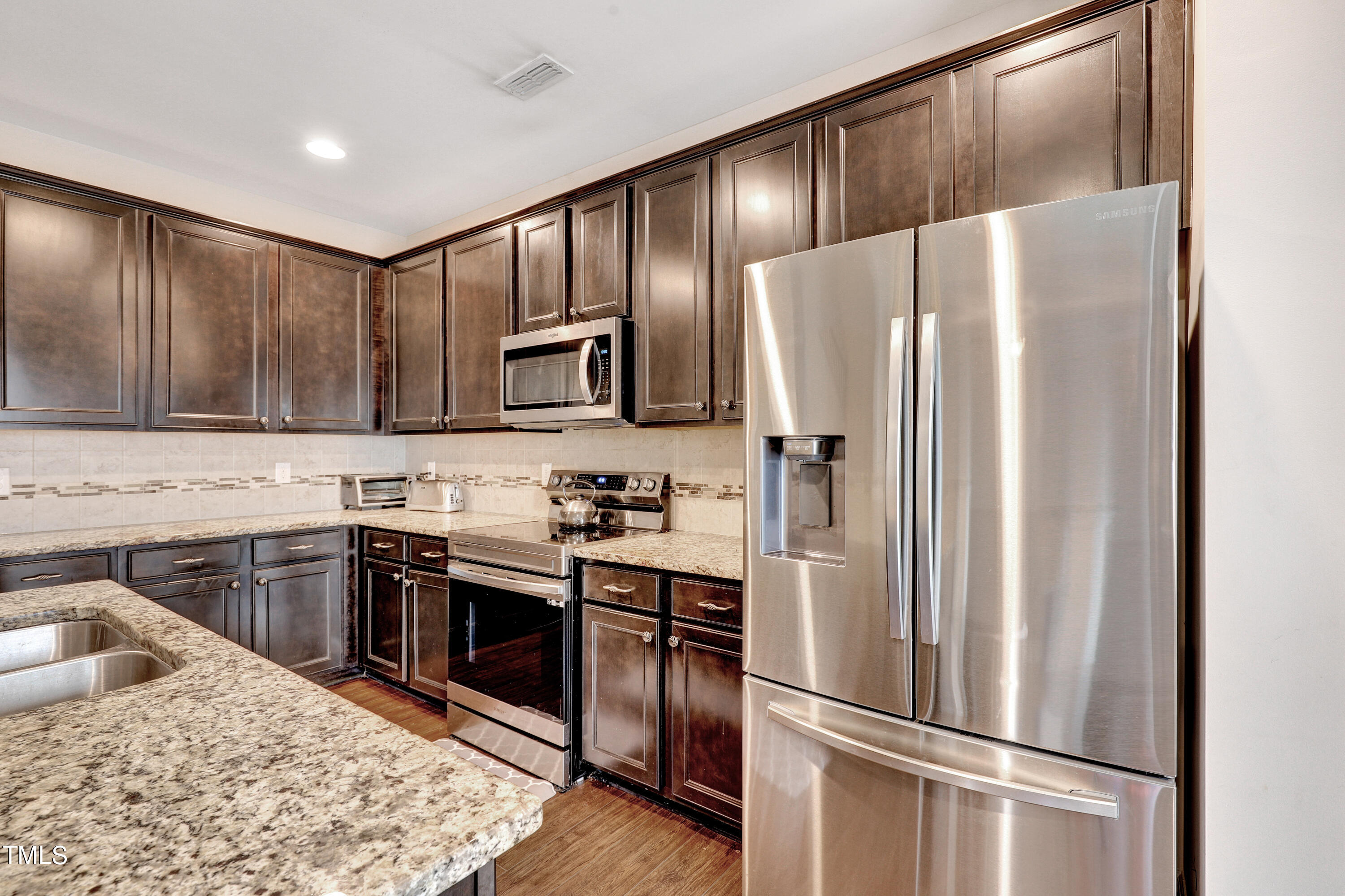 329 Hope Valley Road Knightdale, NC 27545 - Photo 12 of 34 a kitchen with granite countertop stainless steel appliances and wooden cabinets