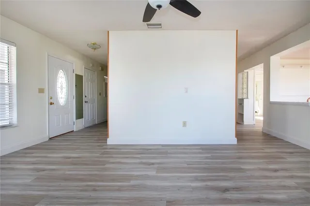 a view of an empty room with wooden floor and a window