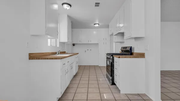a kitchen with a sink a stove top oven and white cabinets
