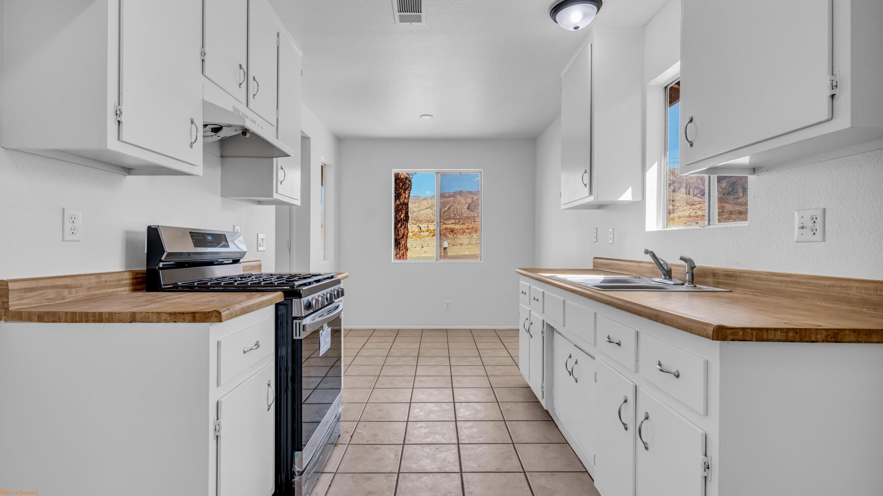 67285 Pierson Boulevard, Unit B Desert Hot Springs, CA 92240 - Photo 17 of 29 a kitchen with granite countertop a sink and a stove