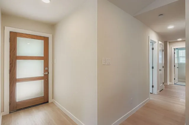 an empty room with wooden floor closet and windows