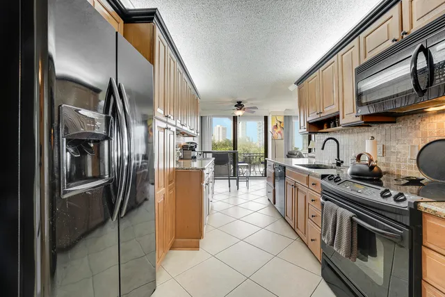 a kitchen with stainless steel appliances granite countertop a refrigerator a stove and a sink with wooden cabinets