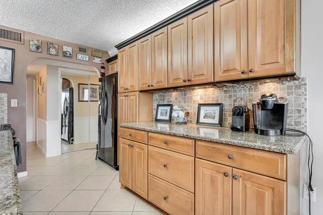 a kitchen with granite countertop stainless steel appliances a sink a refrigerator and cabinets