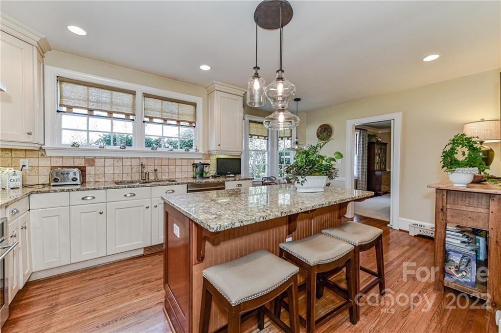 2700 Normandy Road Charlotte, NC 28209 - Photo 20 of 42 a large kitchen with granite countertop a stove a sink a kitchen island with chairs and wooden floor