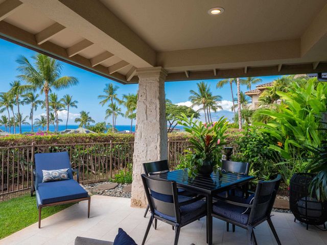 a living room with furniture potted plant and kitchen view