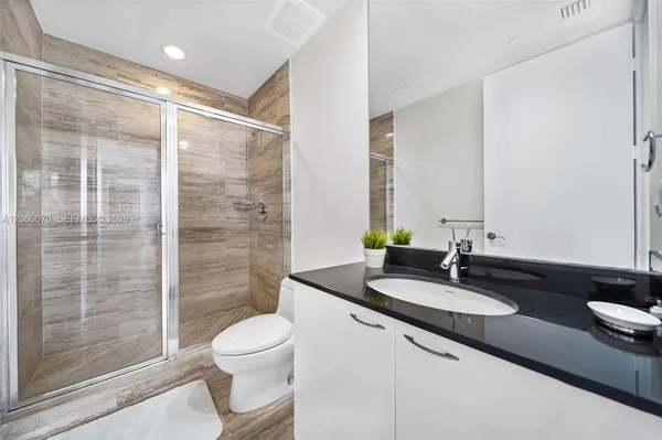 a bathroom with a granite countertop sink toilet a mirror and shower