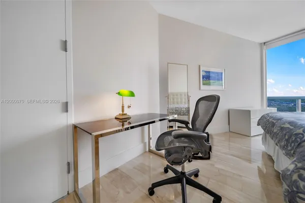a bedroom with a bed large window with desk and chair