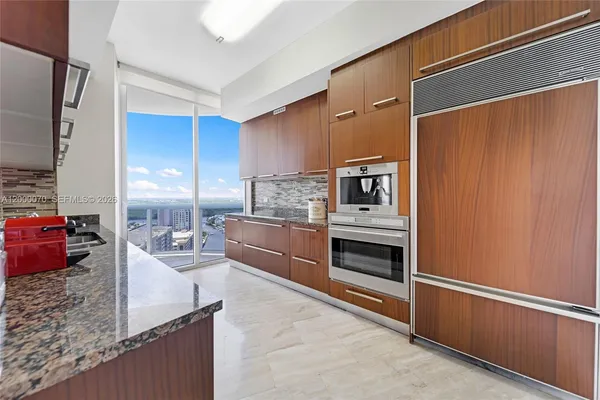 a kitchen with stainless steel appliances granite countertop a refrigerator a stove and a sink with wooden floor