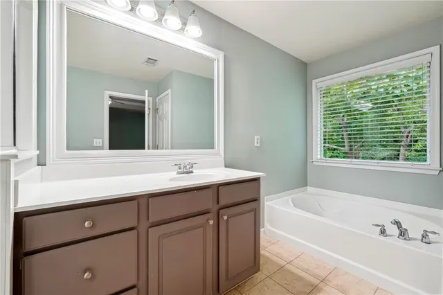 a bathroom with a tub a sink and mirror