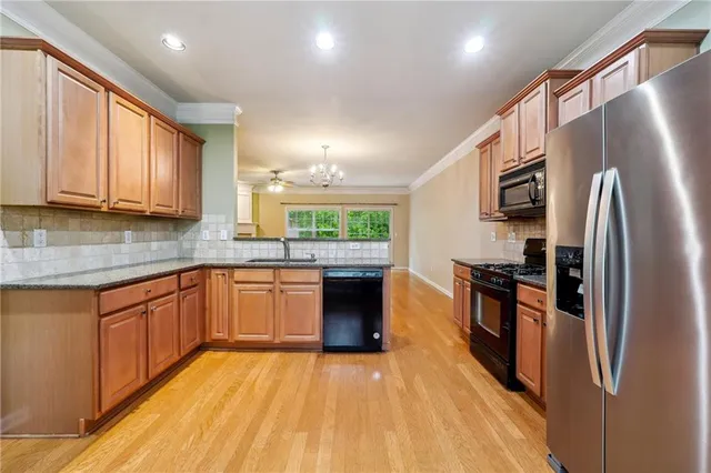 a kitchen with stainless steel appliances granite countertop a refrigerator a stove top oven a sink and dishwasher