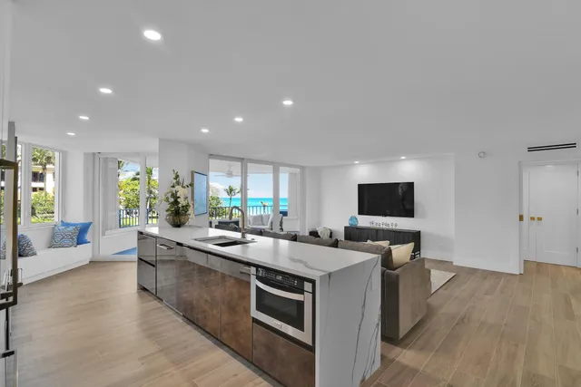 a large kitchen with stainless steel appliances a large counter top a couch and a view of living room