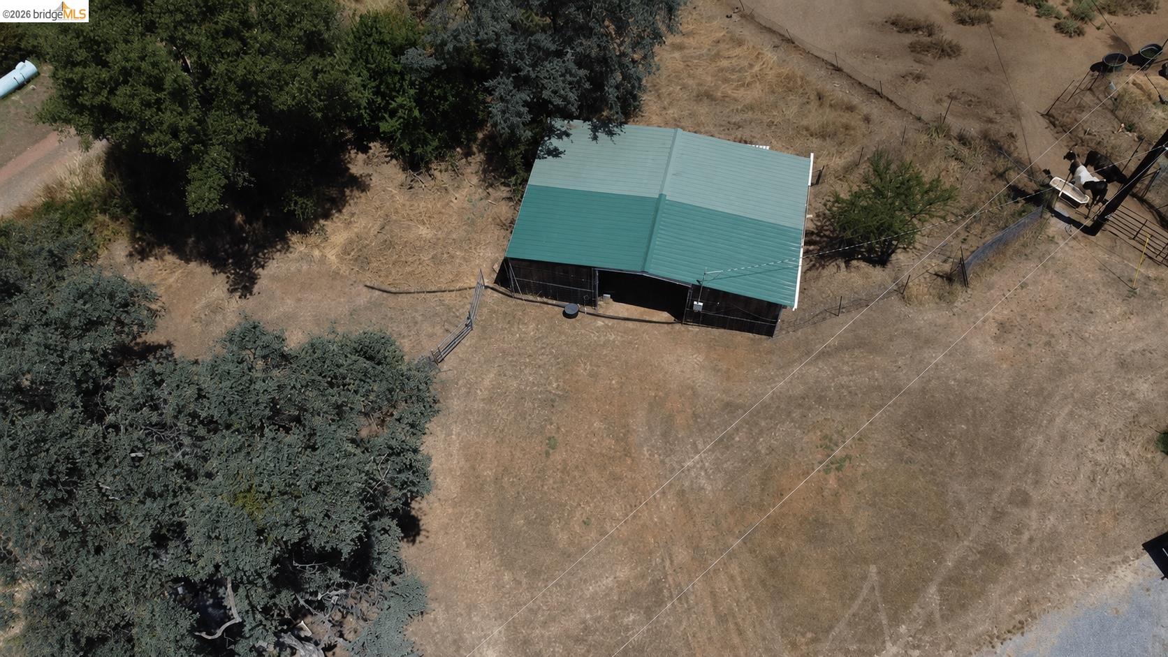18195 Wards Ferry Road Sonora, CA 95370 - Photo 5 of 67 Large agricultural building with a green metal roof, set within an expansive, natural landscape