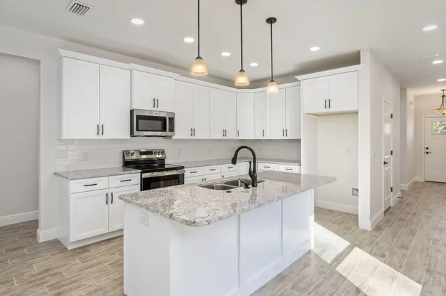 a kitchen with stainless steel appliances granite countertop a sink a stove a refrigerator a center island a stove and cabinets