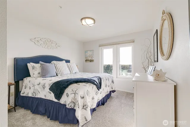 a spacious bedroom with a bed a mirror and windows