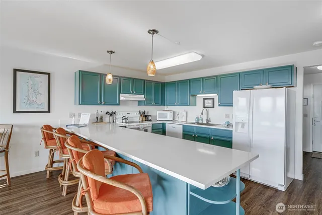 a kitchen with stainless steel appliances a table chairs refrigerator and wooden cabinets