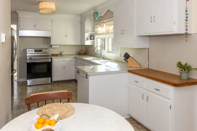 a kitchen with granite countertop a sink a stove and cabinets