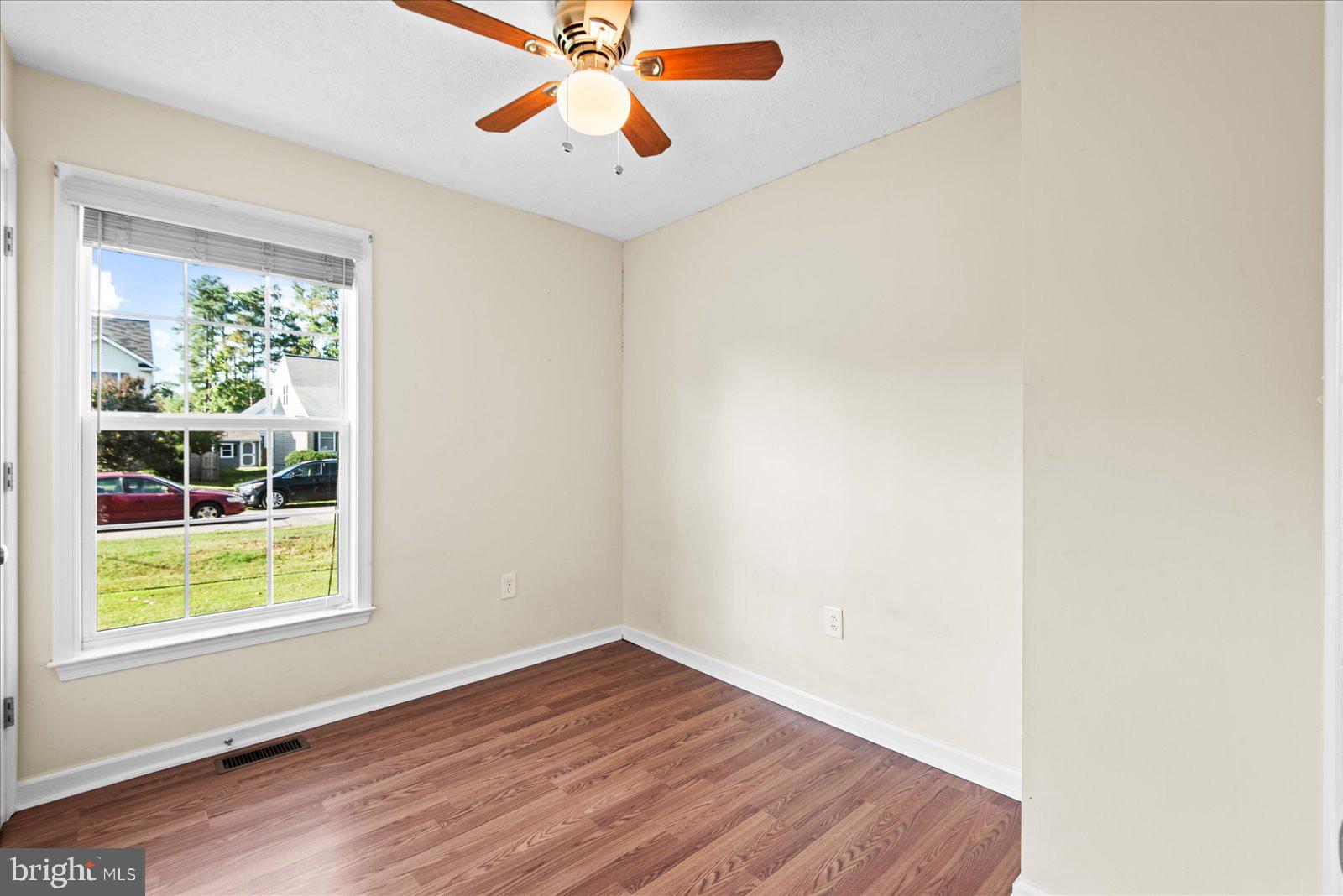 310 3rd Street Colonial Beach, VA 22443 - Photo 29 of 38 an empty room with wooden floor chandelier fan and windows