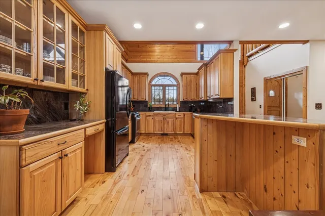 a kitchen with stainless steel appliances granite countertop a refrigerator a stove a sink dishwasher and wooden cabinets with wooden floor