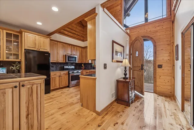 a kitchen with stainless steel appliances granite countertop a refrigerator a stove top oven a sink dishwasher and wooden cabinets