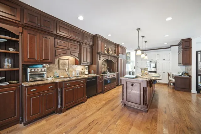 a kitchen with stainless steel appliances granite countertop a sink a stove and a refrigerator