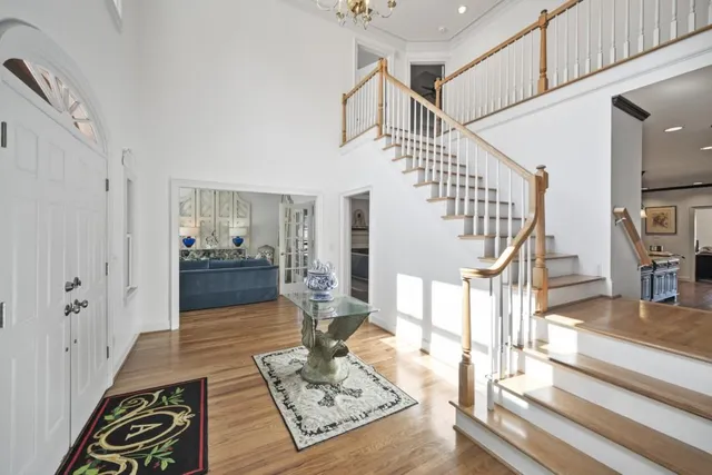 a living room with white couches and a dining table with wooden floor