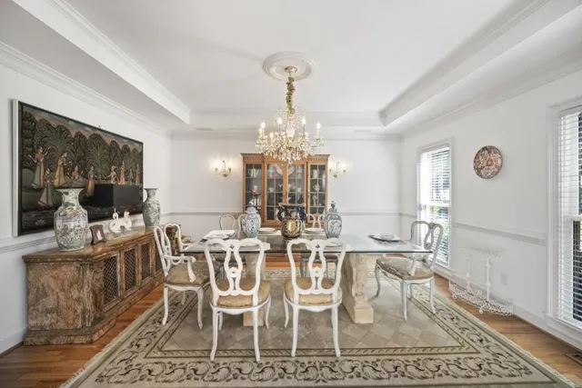 a dining room with wooden floor a chandelier a wooden table and chairs