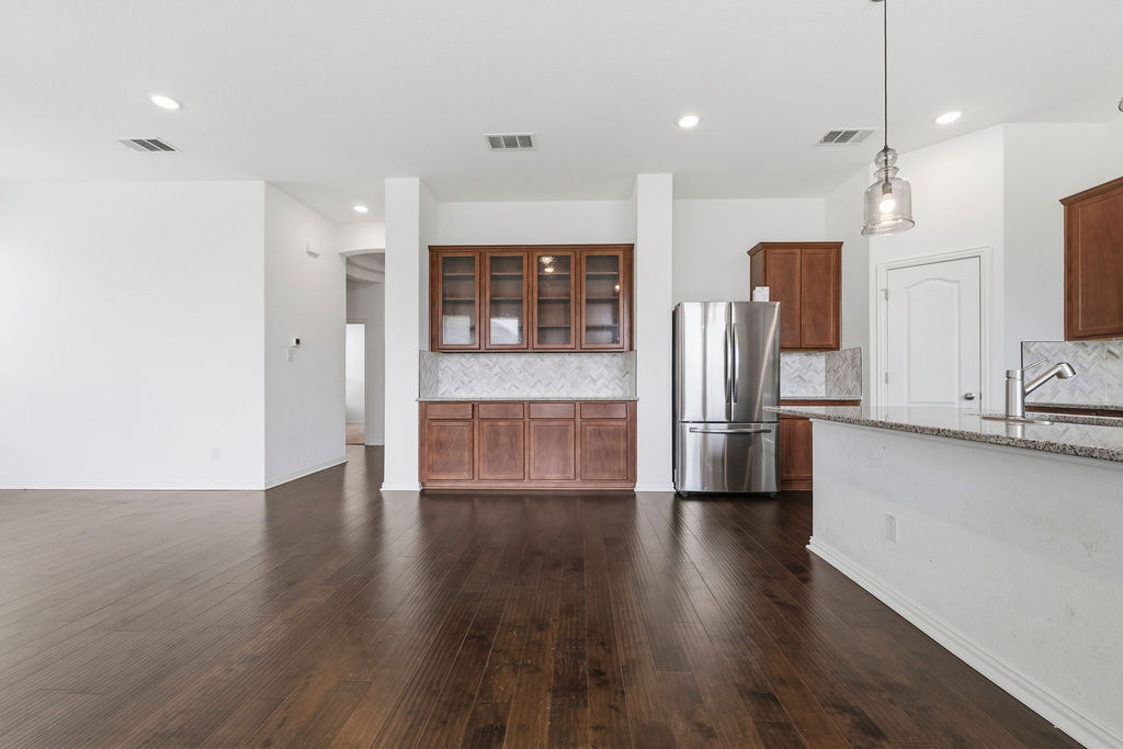1005 Ridge Runner Drive Georgetown, TX 78628 - Photo 28 of 32 Open-concept living area featuring rich wood-finish flooring, recessed lighting, and a kitchen island with a stone-look countertop