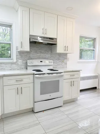 a kitchen with stainless steel appliances granite countertop white cabinets sink and window