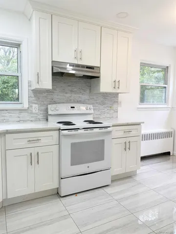 a kitchen with stainless steel appliances granite countertop white cabinets sink and window