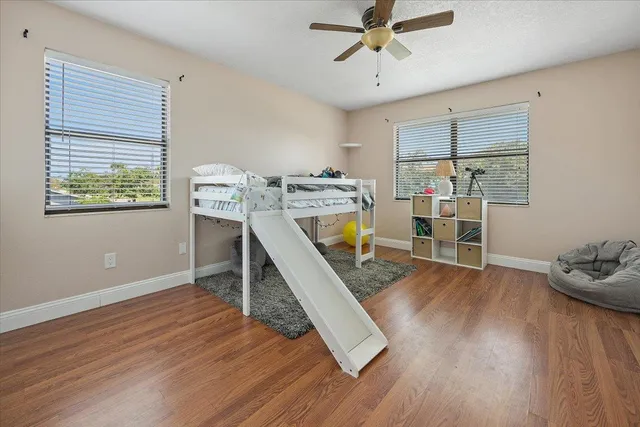 a view of a room with wooden floor ceiling fan and windows