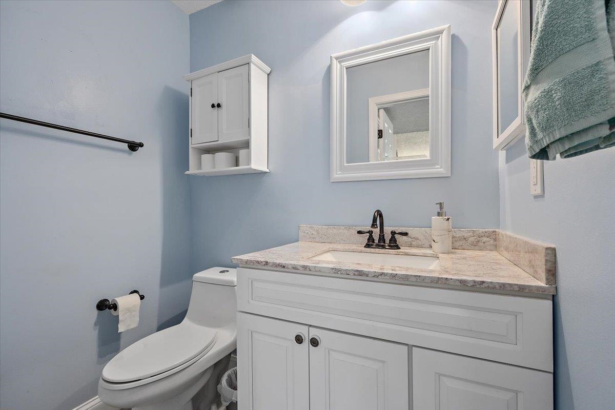 124 Rio Del Mar Street, Unit C St. Augustine, FL 32080 - Photo 9 of 27 a bathroom with a granite countertop sink mirror vanity and toilet