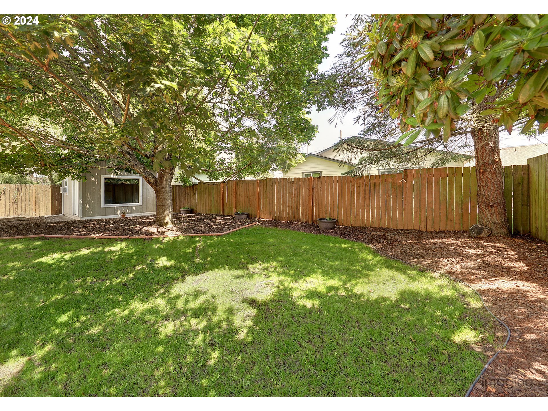 4424 Northeast 115th Avenue Portland, OR 97220 - Photo 17 of 24 a view of a backyard with large trees and wooden fence