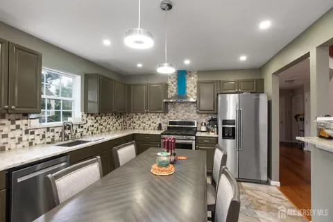 a kitchen with stainless steel appliances kitchen island granite countertop a refrigerator and a sink