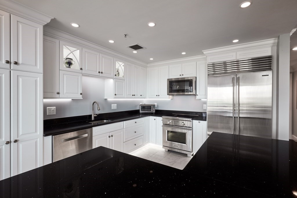 197 8th Street, Unit PH230 Boston, MA 02129 - Photo 6 of 29 a kitchen with granite countertop white cabinets and stainless steel appliances