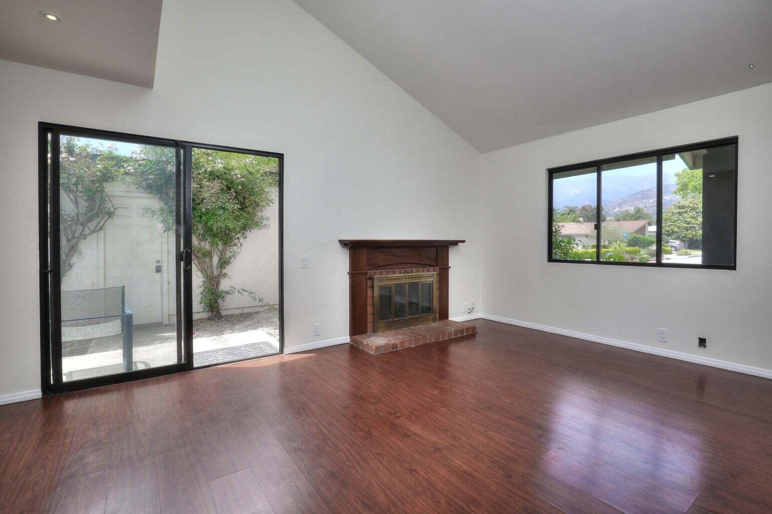 4715 Aragon Drive Carpinteria, CA 93013 - Photo 3 of 29 an empty room with wooden floor fireplace and windows