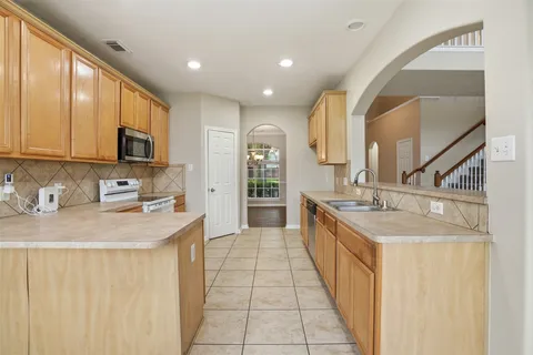 a large kitchen with stainless steel appliances granite countertop a sink and cabinets