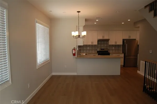 a view of a kitchen with kitchen island white cabinets and stainless steel appliances