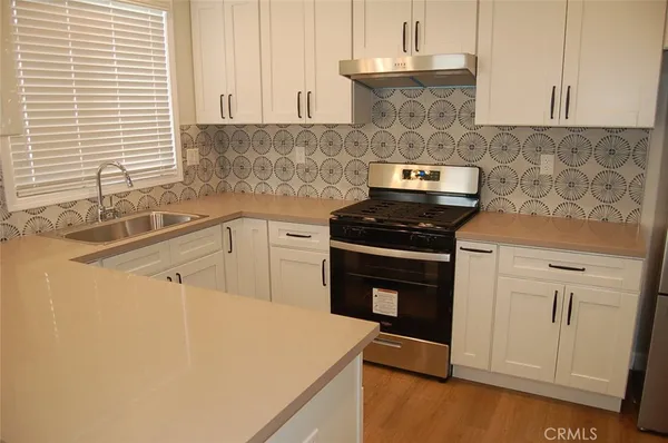 a kitchen with granite countertop a sink a stove and cabinets