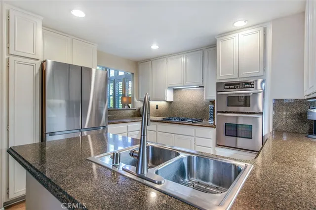a kitchen with granite countertop a refrigerator and a sink