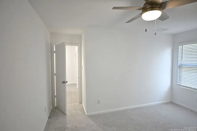 an empty room with a fan & a ceiling fan