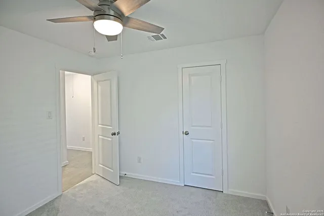 an empty room with a window and ceiling fan