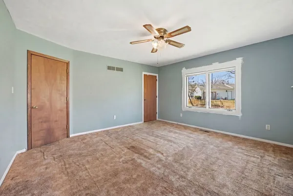 a view of a big room with windows and chandelier fan