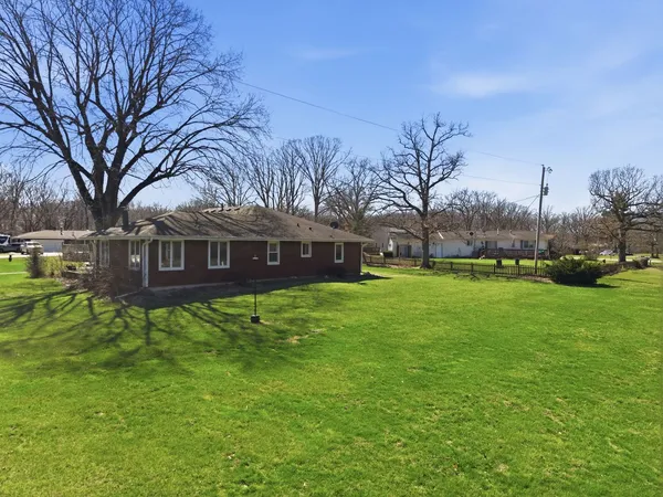 a view of a white house with a big yard and large trees
