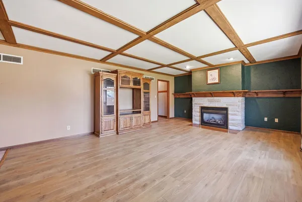 a view of an empty room with wooden floor fireplace and a window